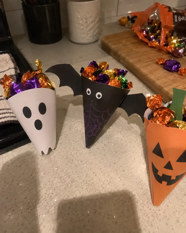 Ghost, bat and pumpkin treat cones on a kitchen counter